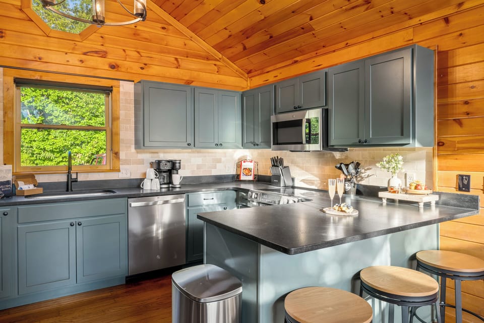 Bright cabin kitchen with island seating, modern finishes, and forest views