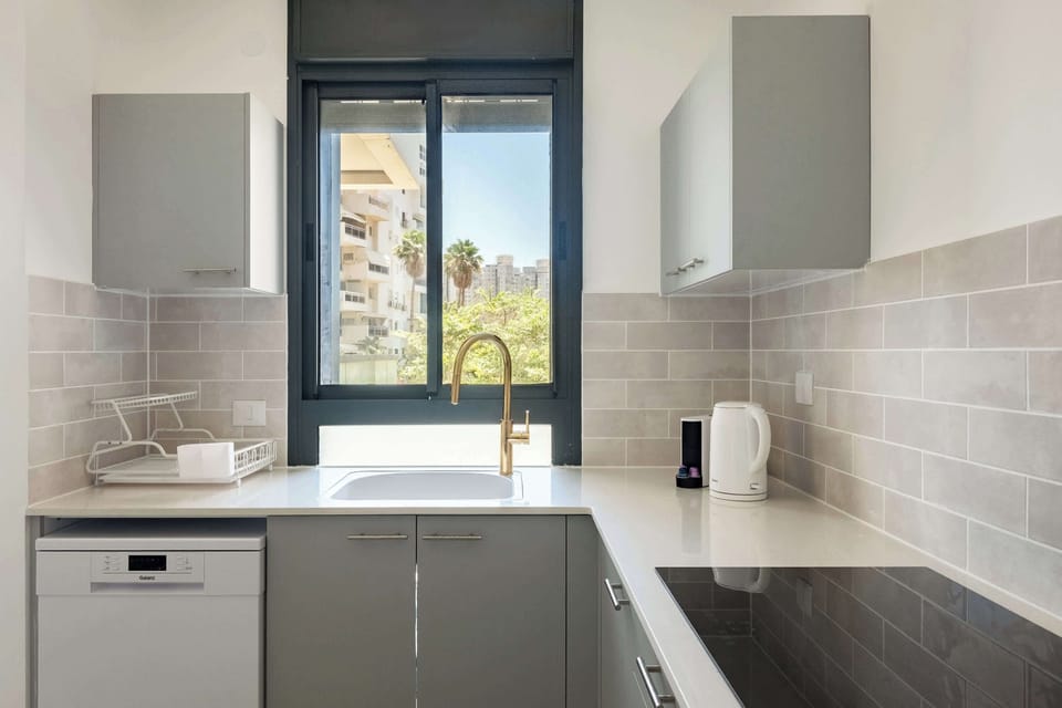 Compact galley kitchen featuring dove-gray lower units, white upper storage, and strategic window placement.

