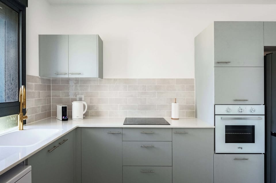 Modern culinary space with two-tone cabinetry, integrated white appliances, tile backsplash, and efficient layout.
