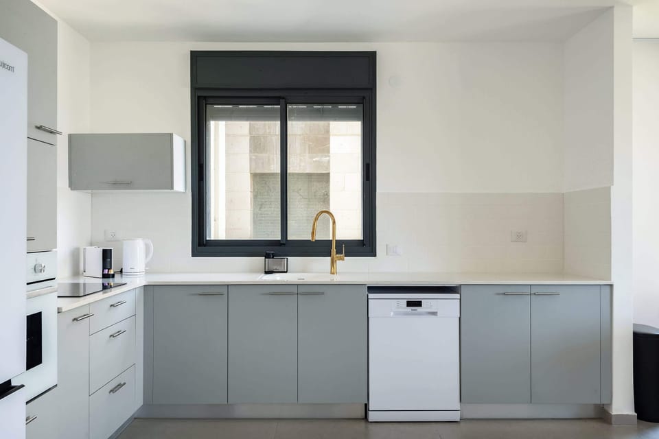 Compact kitchen with gray cabinetry, stainless steel sink, window view, and organized workspace layout.
