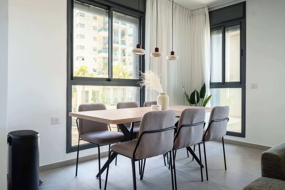 Elegant dining space with wooden table, contemporary chairs, pendant lights, and expansive window views.
