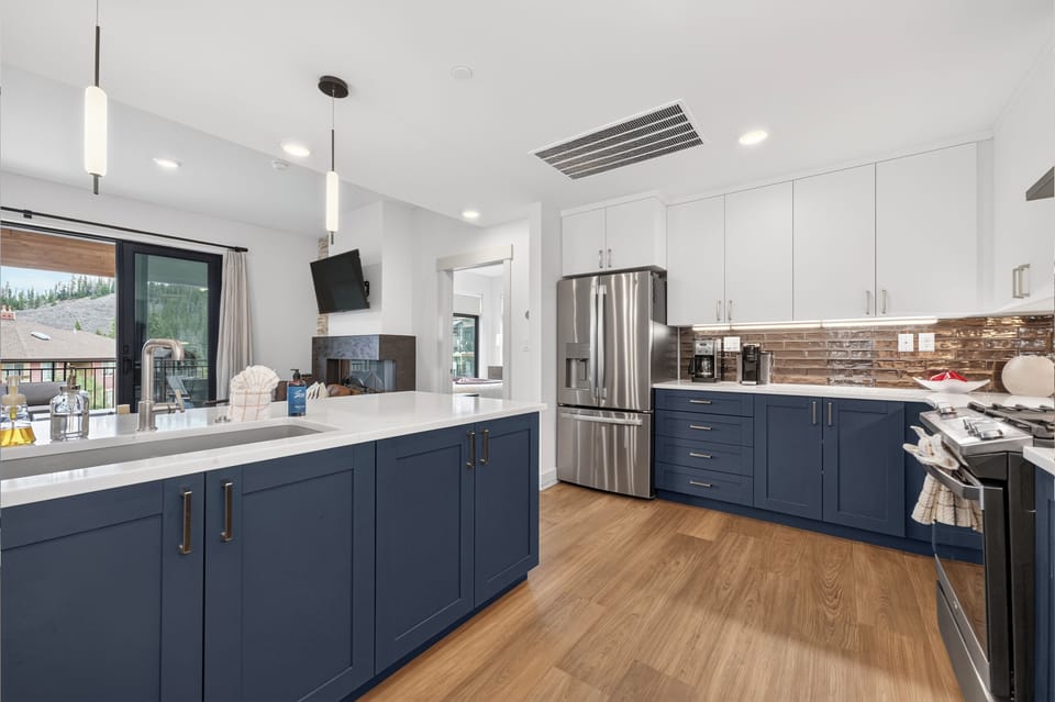 Picture yourself cooking in this stunning chef's kitchen with sleek navy cabinetry, stainless steel appliances, and warm wood floors—perfect for whipping up your favorite vacation meals together.