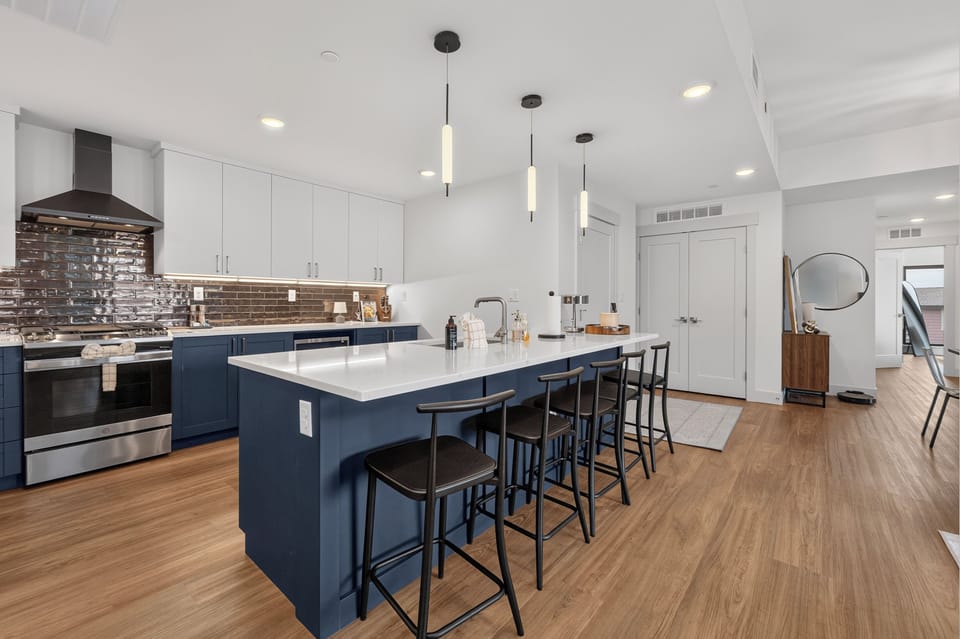 Your fully equipped kitchen features modern appliances, a spacious island with seating for six, and sleek pendant lighting—perfect for preparing meals and gathering with loved ones.