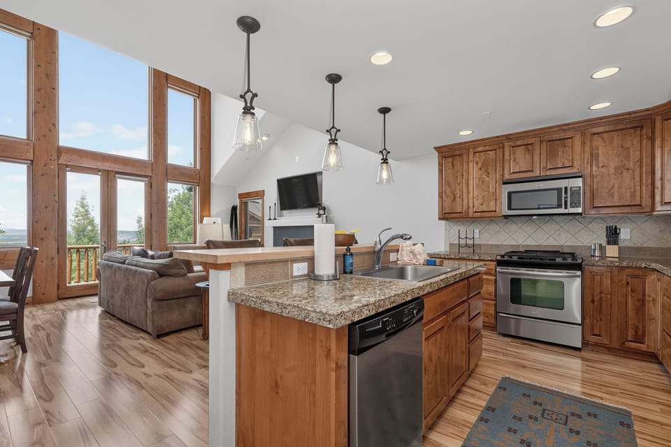 Gather in this bright open-concept space where your kitchen flows seamlessly into the living area. Granite counters, stainless appliances, and soaring ceilings with mountain views set the scene for memorable meals.