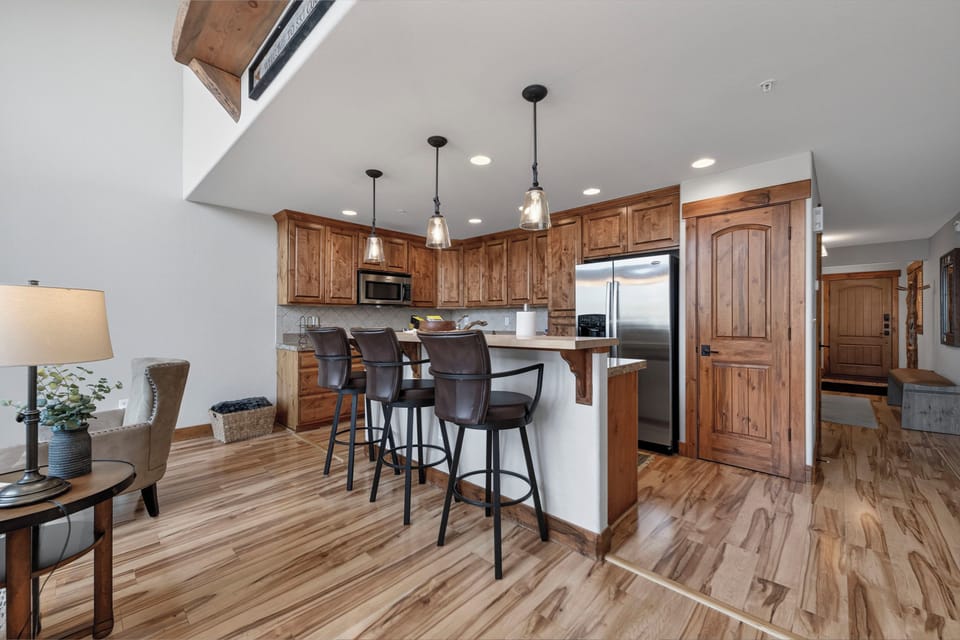 Gather at the spacious kitchen island, where warm wood tones and modern appliances blend seamlessly for your mountain retreat. Perfect for morning coffee or evening cocktails with friends.