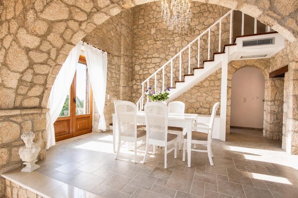 Stone dining room with a white table set next to a staircase.