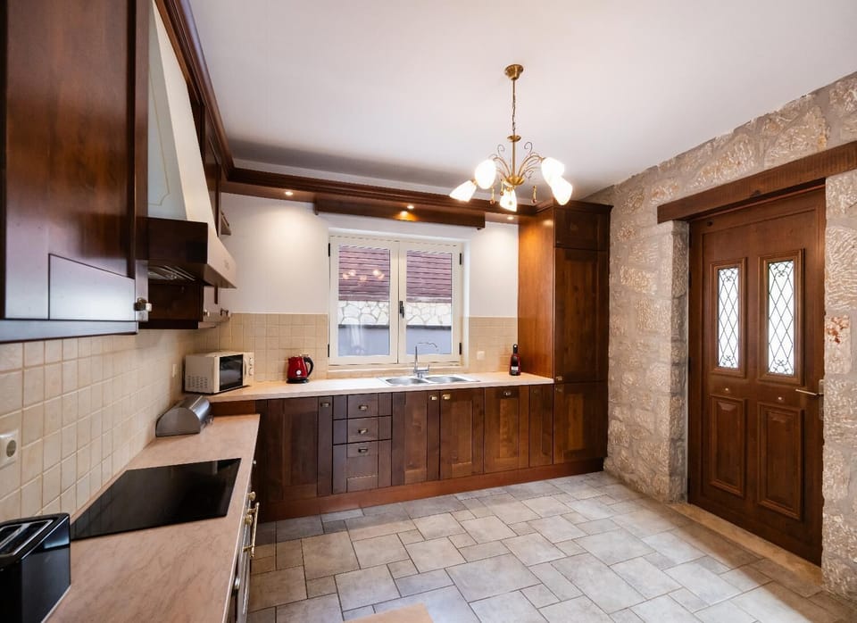 Kitchen area with rich wooden cabinets, tiled floors, and a stone wall accent.