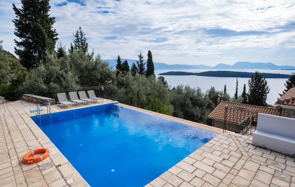 Infinity swimming pool with sun loungers overlooking a scenic island bay.