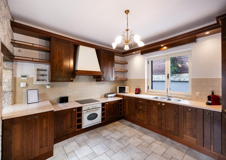 Fully equipped kitchen with rich wooden cabinetry and tiled flooring.