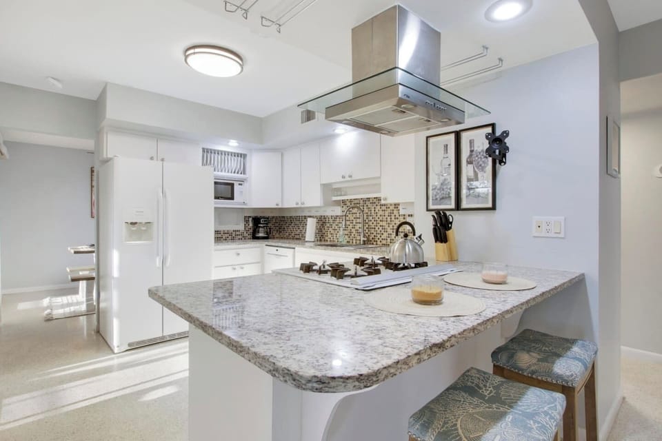 Kitchen with granite counters, stove and bar area.