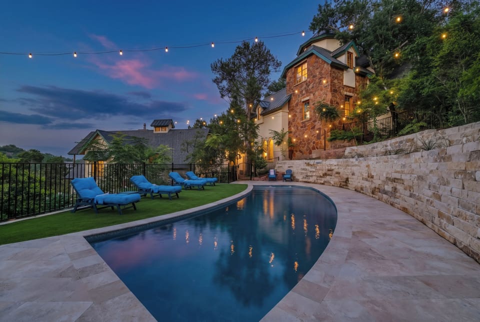 Twilight pool glowing beneath the lit Austin castle estate