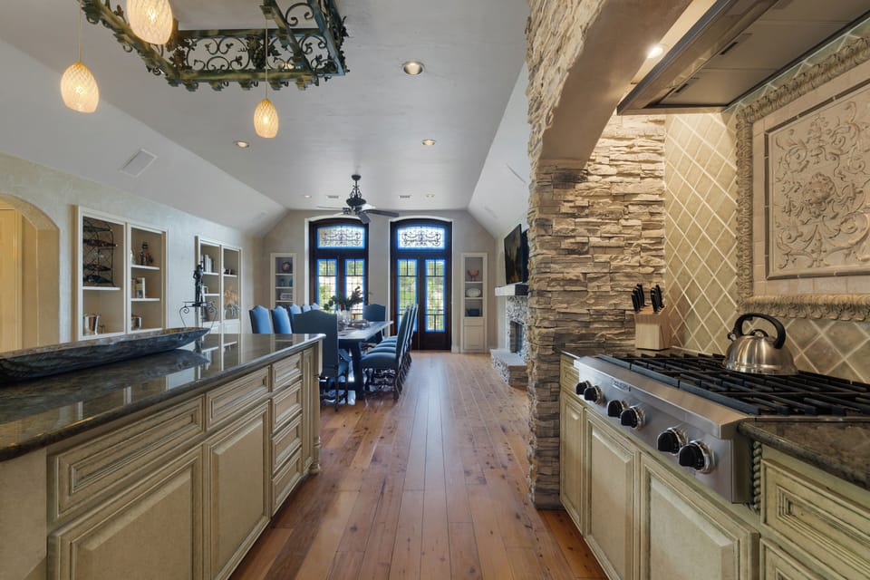 Stacked stone arch framing the gas range and granite island