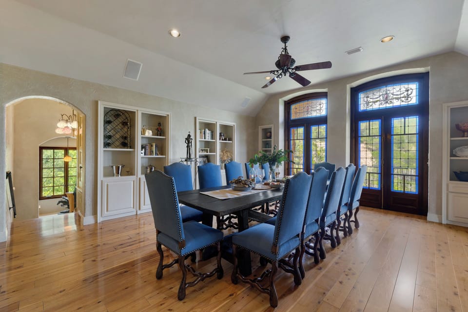 Long dining table seating twelve beneath stained glass garden doors