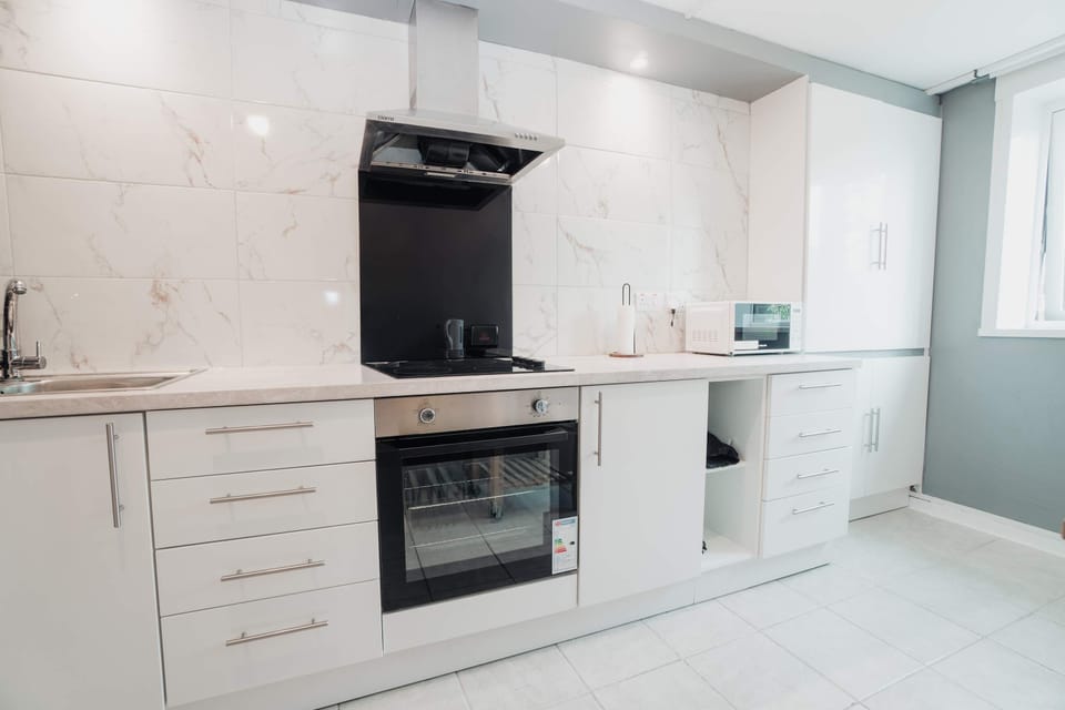Electric oven, hob and extractor, with clear worktop either side. Room to make tomorrow's sandwiches while dinner is on, which is the whole point of not being in a hotel.