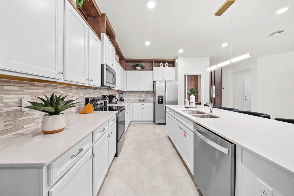 Enjoy a spacious kitchen with sleek white cabinetry and soft beige countertops that create a bright atmosphere. Modern stainless steel appliances provide style and functionality, complemented by warm wood accents for added charm.
