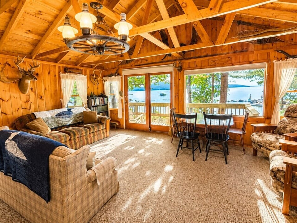 Cozy lakefront living room with panoramic water views and rustic wood interior.