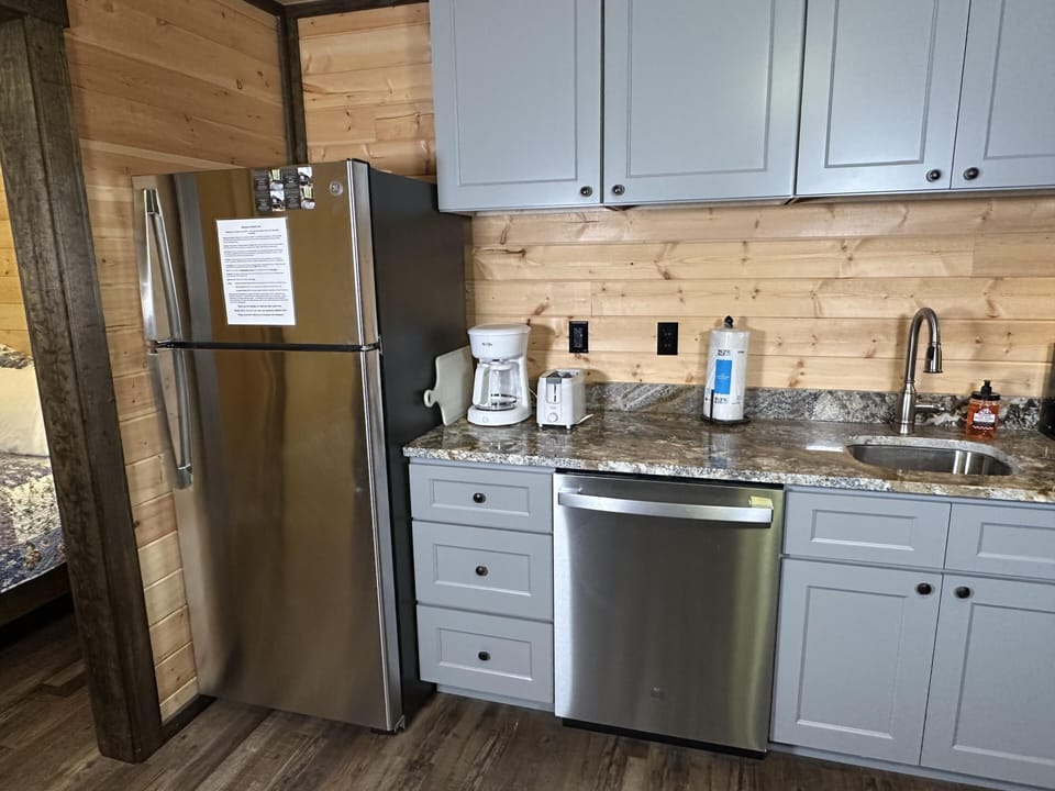Stainless steel appliances line the kitchen with gray cabinets, granite countertops, and light wood paneling.