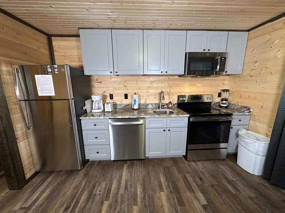 Gray cabinets with black knobs line the kitchen wall above granite countertops and stainless steel appliances.