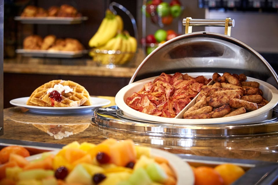 Indulge in a delicious breakfast spread with crispy bacon, savory sausage, and fresh fruit to kickstart your morning.