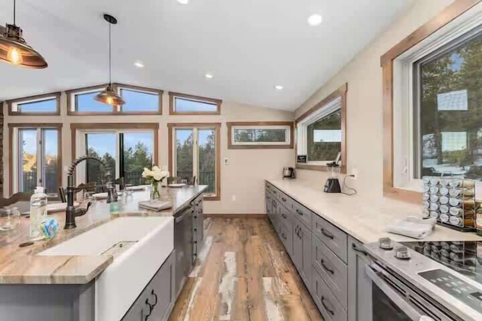 Bright kitchen with oversized island, modern finishes, and forest views