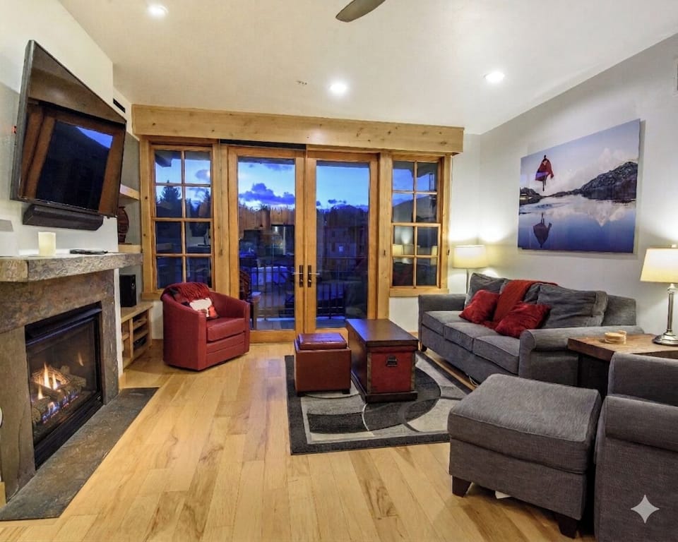 Cozy mountain-style living room with fireplace and balcony views