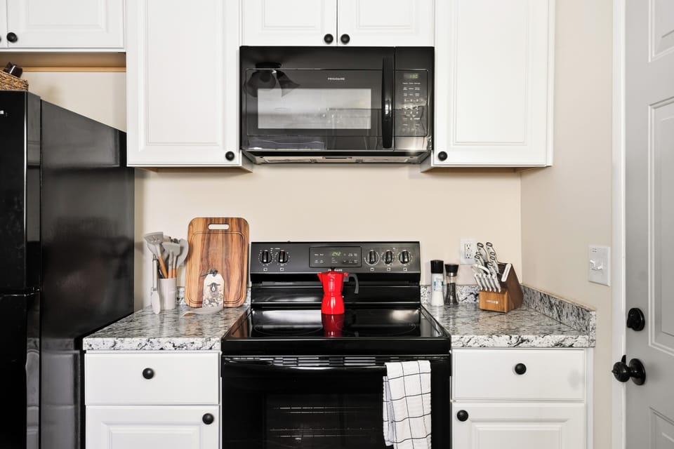 Bright, fully equipped kitchen with granite counters and sleek black appliances
