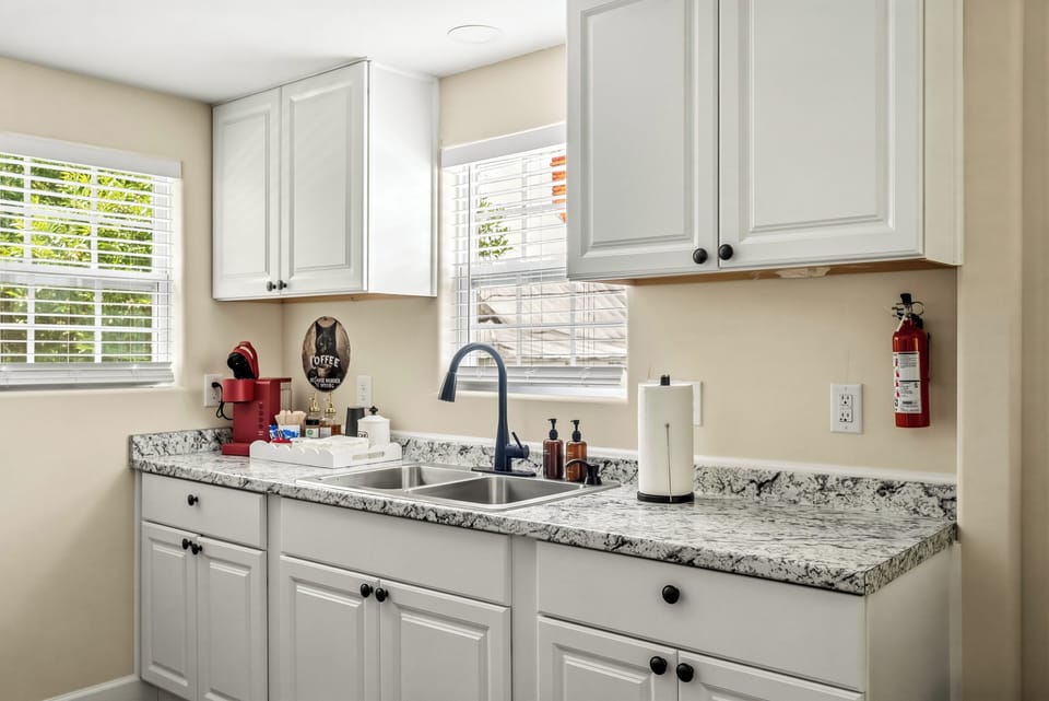 Bright kitchenette with granite counters, coffee station, and sunny windows