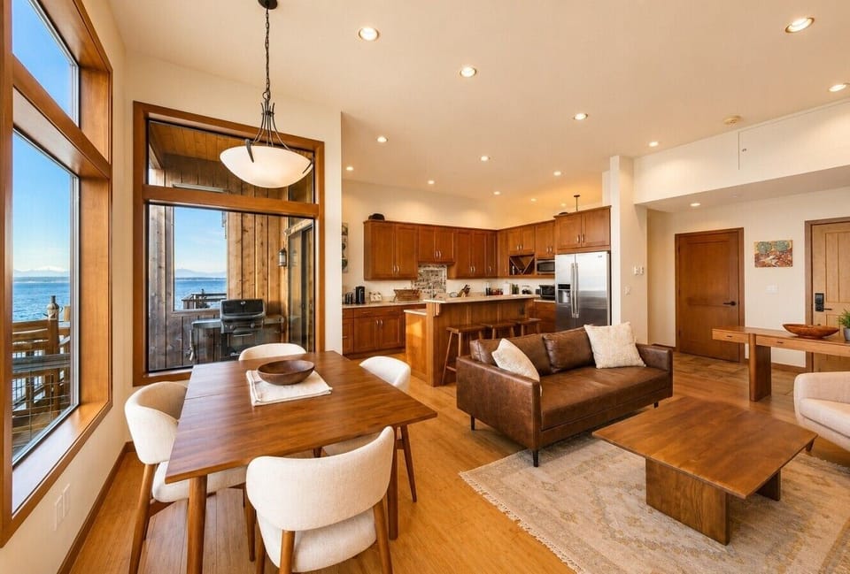 Elegant dining and living area with expansive windows overlooking the water