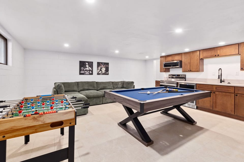 Dedicated Game Room with a kitchenette, 55" smart TV, pool table, foosball table, and a comfortable couch.