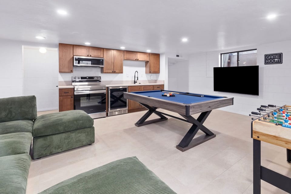 Dedicated Game Room with a kitchenette, 55" smart TV, pool table, foosball table, and a comfortable couch.