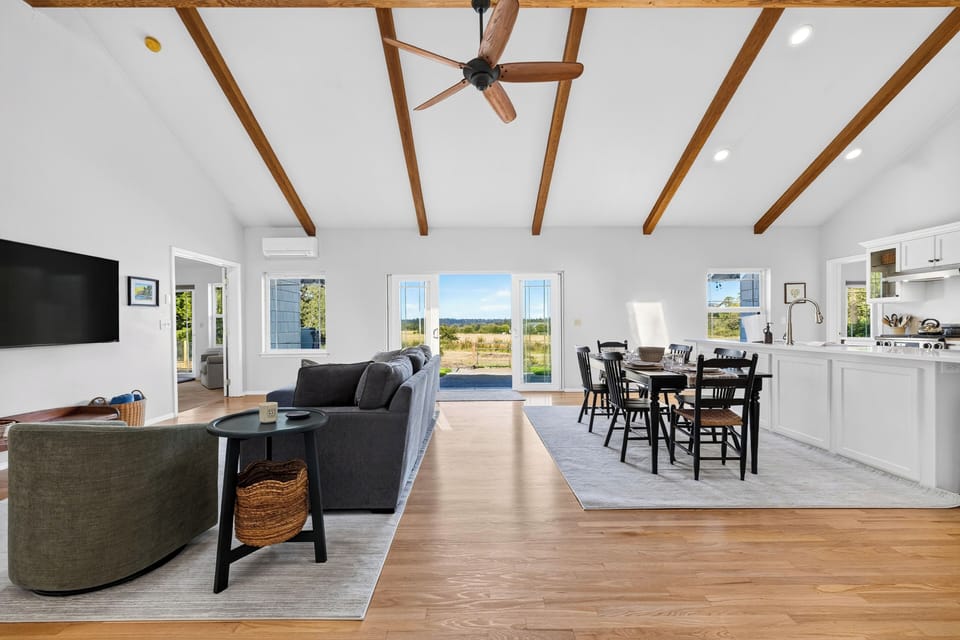 Bright, wide shot of the main living space connecting seamlessly to the dining area and kitchen.