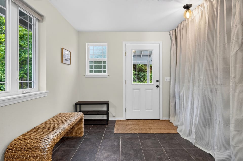 A tiled mudroom/foyer entryway with a bench and front door.