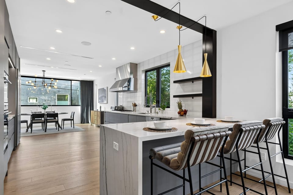 Open kitchen with a waterfall island, bar seating, and sculptural pendant lighting.