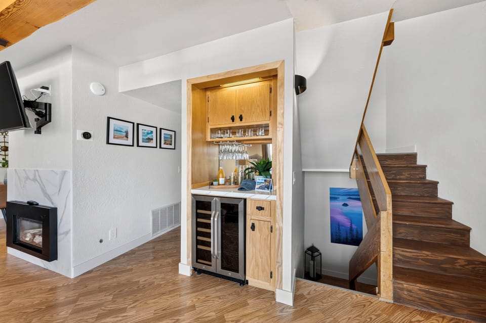 Built-in beverage bar with glassware storage, wine fridge, and convenient access between the living area and stairs.