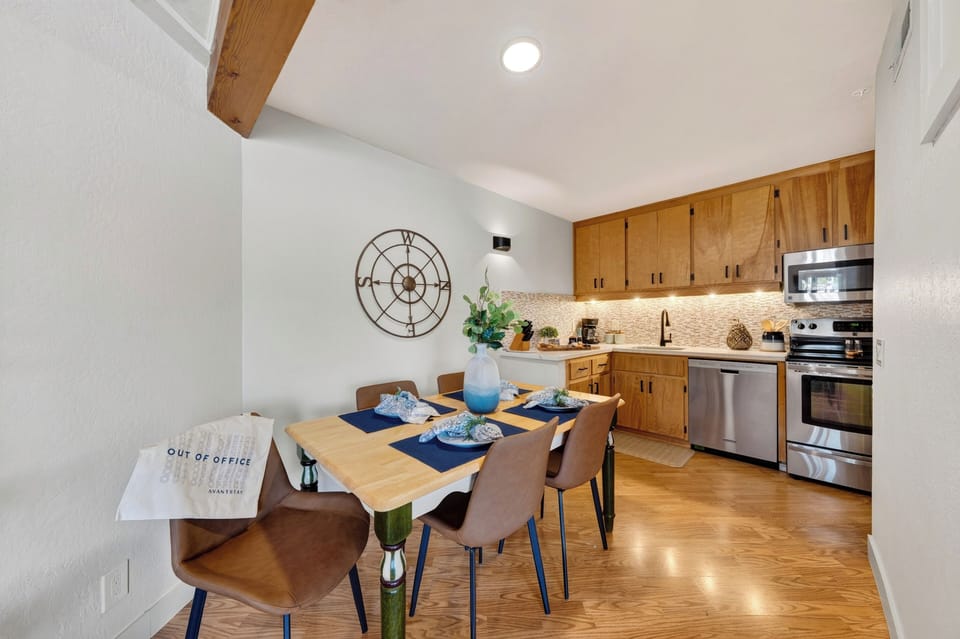 Dining area and full kitchen with warm wood cabinetry, stainless appliances, and seating for four.