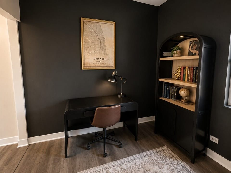 Dedicated office space with dark accent walls, Chicago artwork, and a stylish setup for remote work or quiet planning.