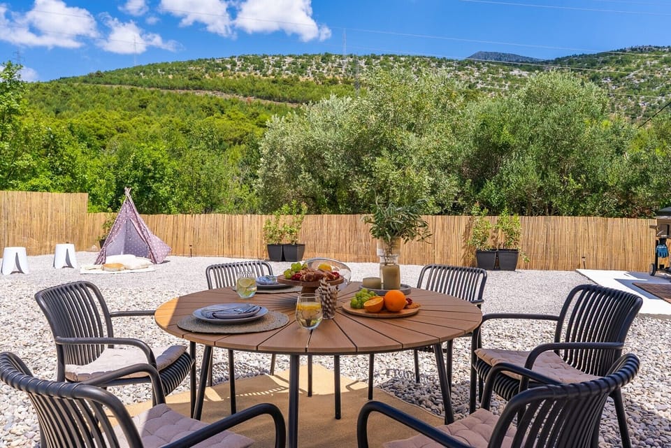 A sun deck area covered with beach pebbles, which includes 6 deck chairs, a dining table, a BBQ (wood/charcoal)