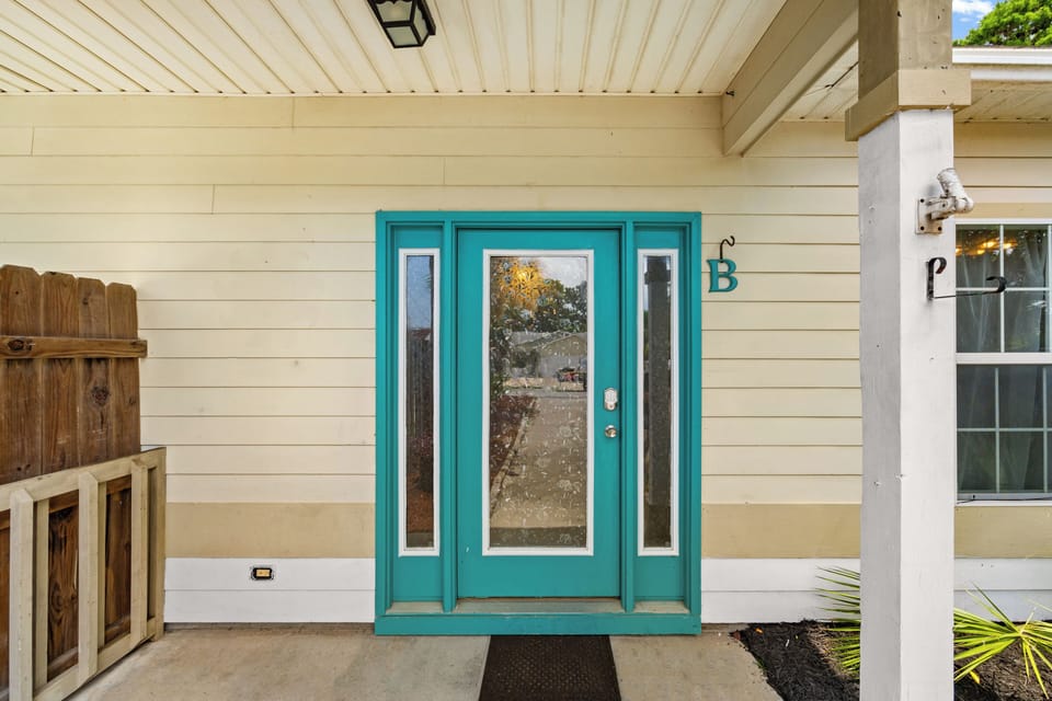 A welcoming entrance with a distinctive teal door and covered porch, clearly marked for easy arrival at this inviting vacation rental property.