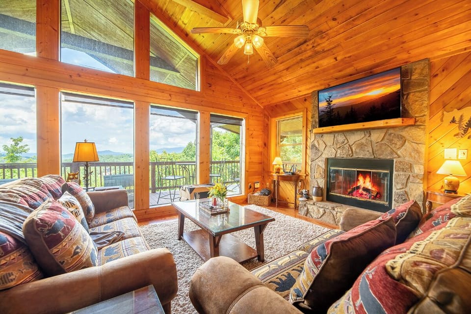 Relax in this warm living space with vaulted pine ceilings, a crackling stone fireplace, and sweeping mountain views—your perfect retreat after a day of adventure.