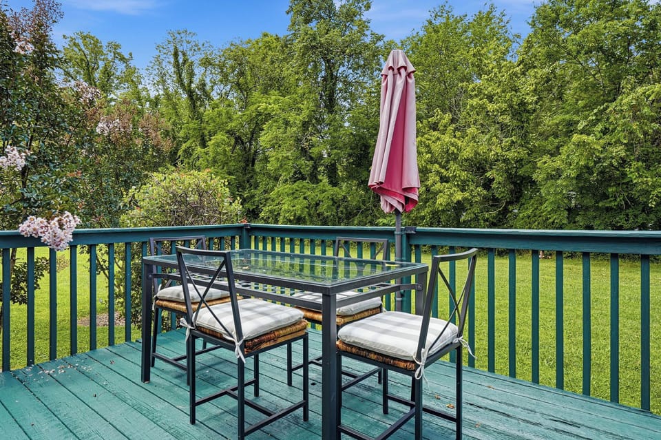 This private balcony overlooks a lush green lawn and mature trees, offering your own peaceful spot to enjoy morning coffee or evening sunsets with comfortable outdoor seating and shade.