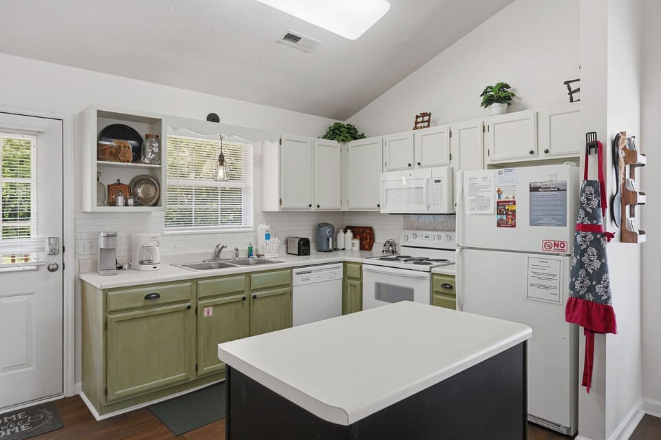 Picture yourself cooking your favorite meal in this bright, welcoming kitchen—fresh plants on the cabinets, plenty of counter space, and a charming two-tone design that makes every culinary moment feel like home.