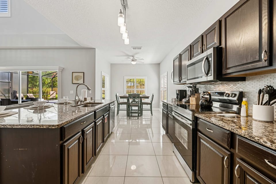 Fully equipped chef's kitchen with granite countertops, stainless steel appliances, and seating for four at the oversized island.