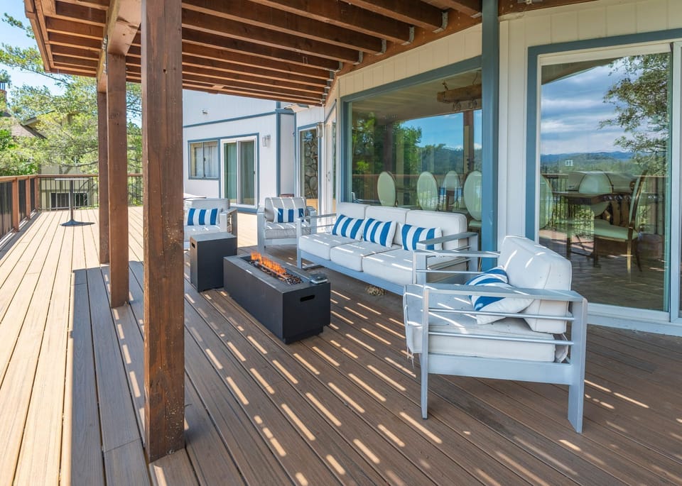 Outdoor deck lounge featuring cushioned seating and an active fire pit table.
