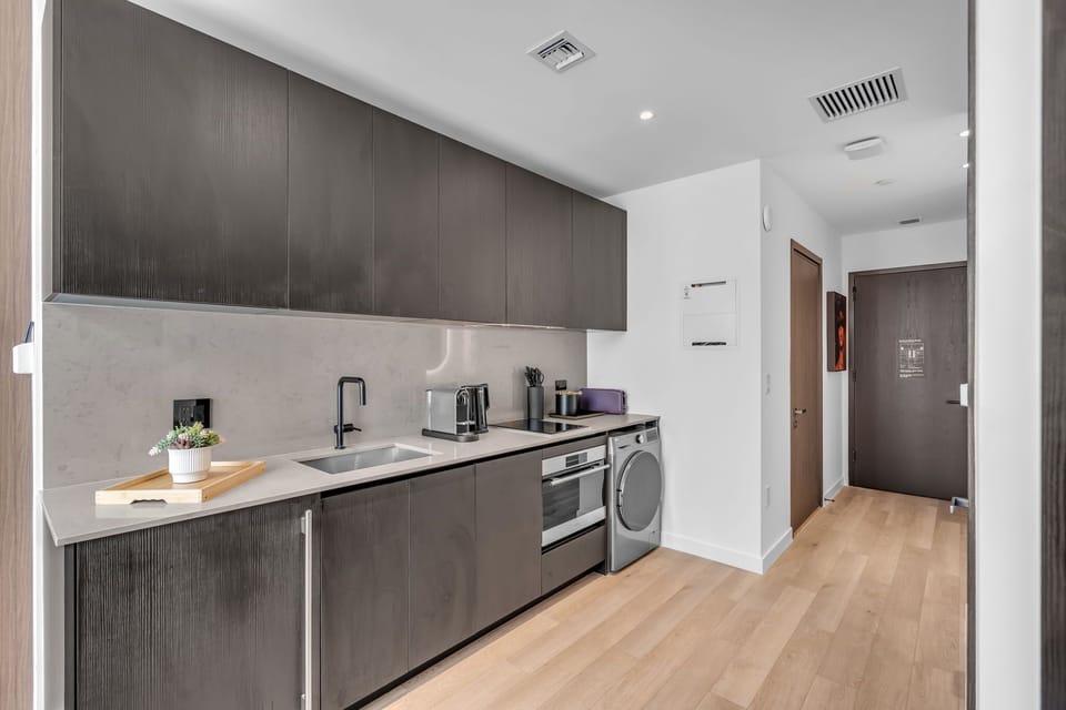Fully equipped kitchen with stainless appliances, cooktop, oven, microwave, and in-unit washer/dryer. Ample cabinet storage and prep space for cooking in during your stay.