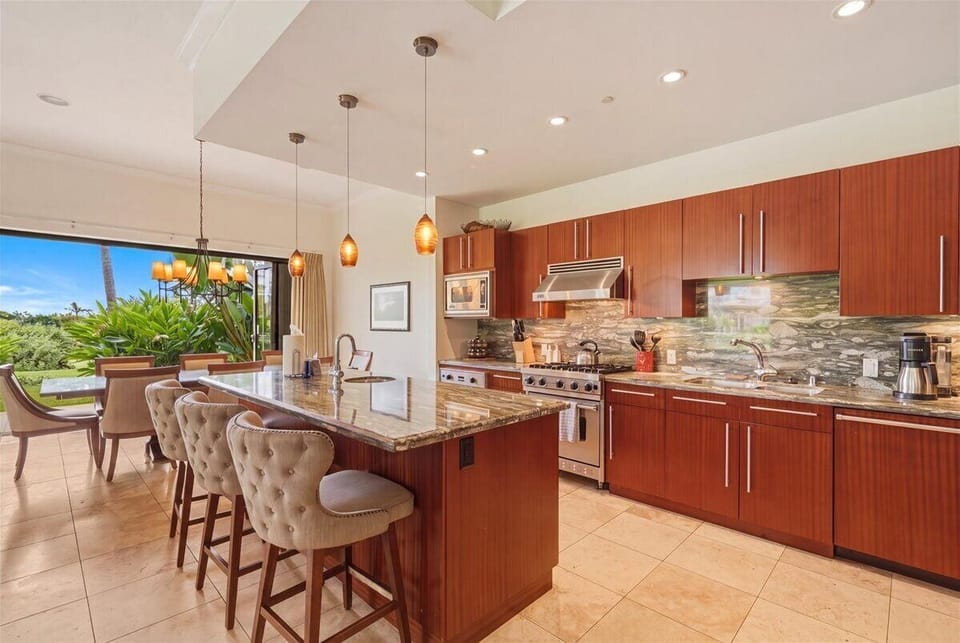 Your spacious kitchen features rich wood cabinets, granite counters, and a breakfast bar where you'll start each morning surrounded by tropical garden views.
