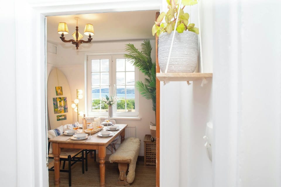 Dining table set for a meal in a bright room, viewed through a doorway