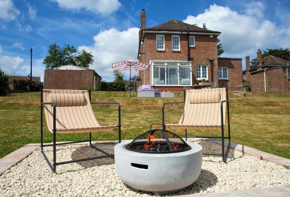 Garden seating area with two outdoor chairs and circular fire pit, lawn and brick home