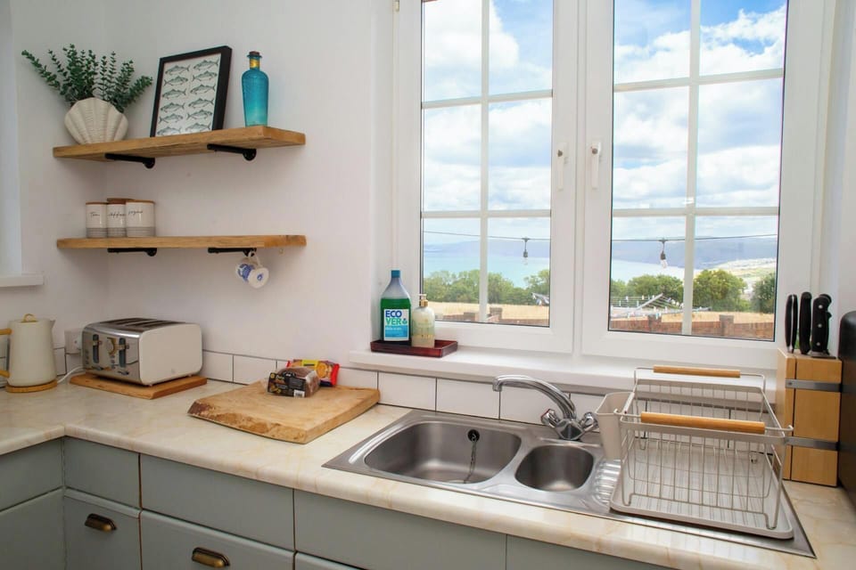 Kitchen sink and drainer beside a window with sea view