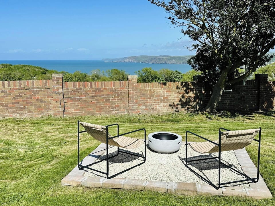 Outdoor sofa seating under a striped parasol on a lawn with sea view