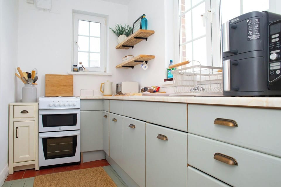 L-shaped kitchen with pale blue cabinets, white oven and wooden worktop